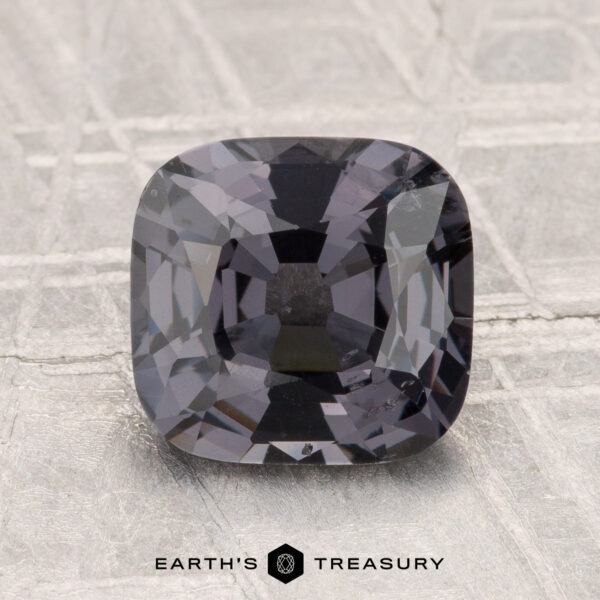 2.39-Carat Spinel A 2.39-carat cushion-cut gray spinel displayed on a textured light gray surface, with the text "EARTH'S TREASURY" at the bottom.