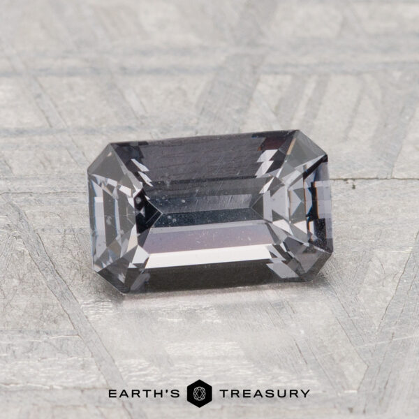 1.50-Carat Spinel A 1.50-carat spinel with beveled edges rests on a textured surface, featuring "Earth's Treasury" and a hexagonal logo below.