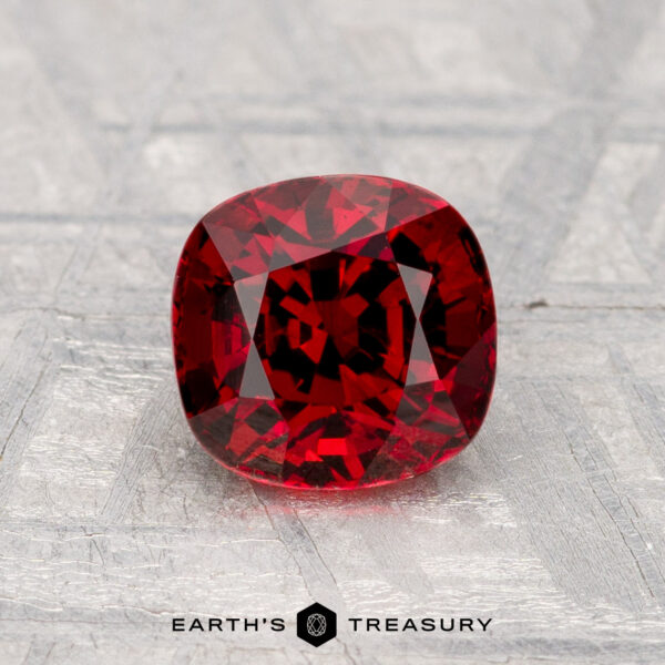 1.49-Carat Spinel A 1.49-carat cushion-cut spinel rests on a textured gray surface, with "Earth's Treasury" displayed at the bottom.