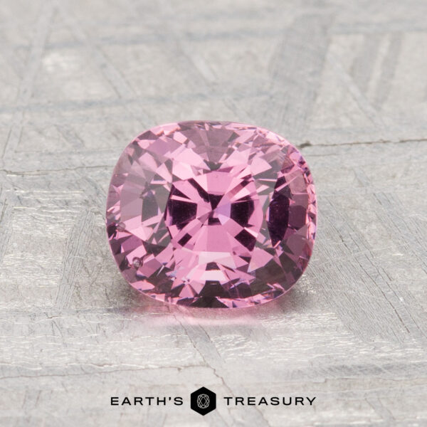 1.44-Carat Spinel A 1.44-carat cushion-cut pink spinel is displayed on a metallic, textured surface with "EARTH'S TREASURY" at the bottom.