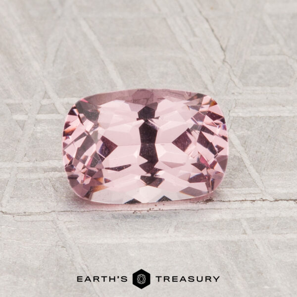 1.24-Carat Spinel A 1.24-carat cushion-cut pink Spinel is displayed on a patterned gray surface, with the text "EARTH'S TREASURY" at the bottom of the image.
