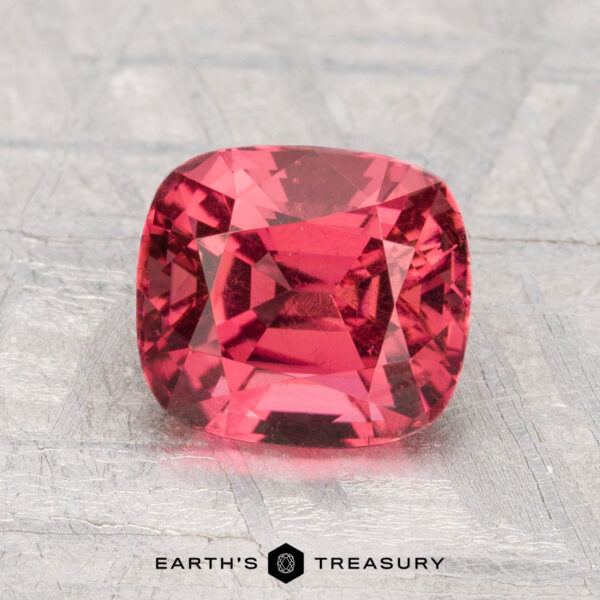1.77-Carat Spinel A 1.77-carat cushion-cut red spinel is displayed on a textured light gray surface, with "Earth's Treasury" at the bottom.