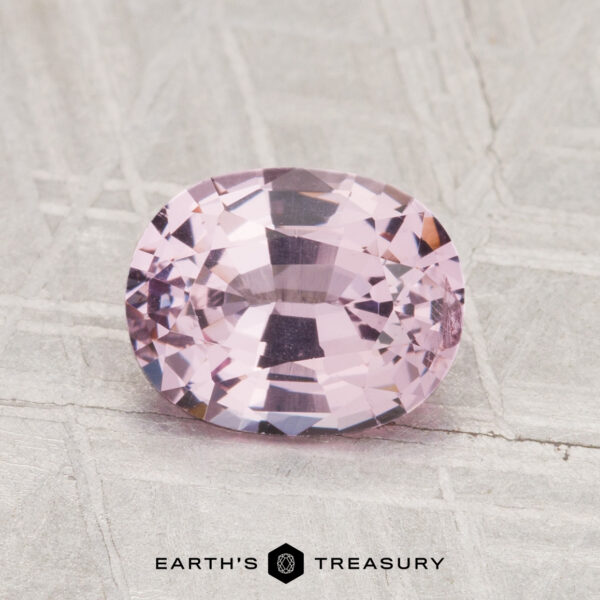 1.42-Carat Spinel A 1.42-carat, faceted oval-cut pink spinel is displayed on a textured light gray surface with the "Earth's Treasury" logo at the bottom.