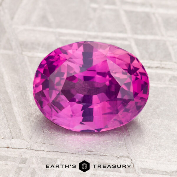 3.04-Carat Sapphire A 3.04-carat, oval-cut sapphire in vivid pink sits on a light-patterned surface with the "EARTH'S TREASURY" text below.