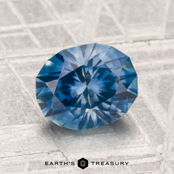 2.08-Carat Montana Sapphire (Heated) A 2.08-carat heated Montana sapphire is showcased on a textured, light surface with "EARTH'S TREASURY" displayed below.
