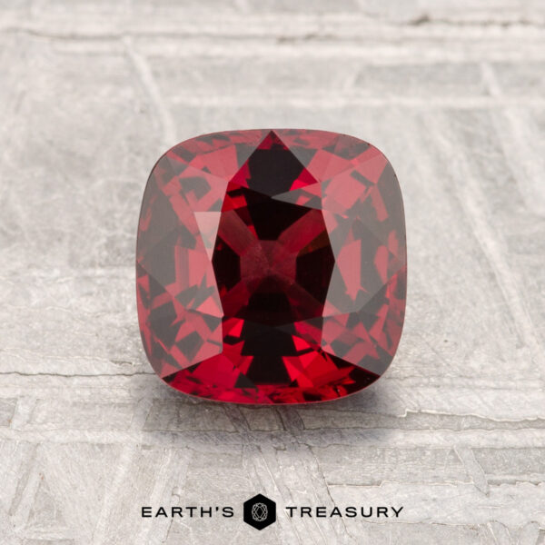 1.67-Carat Spinel A 1.67-carat cushion-cut spinel is shown on a light gray textured surface with the text "Earth's Treasury" below.