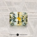 A rectangular, multi-colored 1.16-carat Montana Sapphire (Heated) with yellow and green hues is displayed on a textured surface with "EARTH'S TREASURY" below.