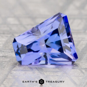 A 3.55-carat unheated tanzanite (zoisite) gemstone in blue-purple hues is displayed on a textured surface with "Earth's Treasury" beneath it.