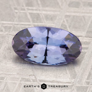 A 3.50-carat unheated tanzanite (zoisite), oval-cut and blue-violet, rests on a gray geometric patterned surface with "EARTH'S TREASURY" at the bottom.