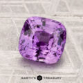 A 2.51-carat faceted purple sapphire rests on a textured metallic surface, with "EARTH'S TREASURY" displayed at the bottom.