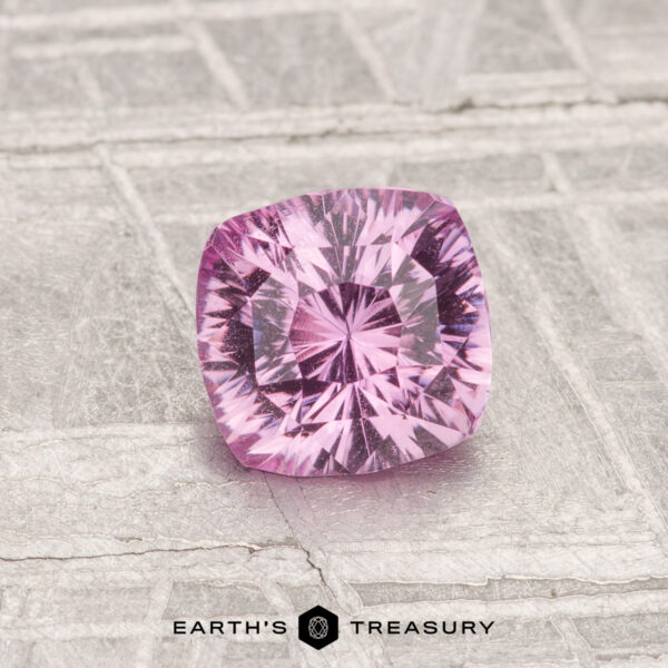 1.06-Carat Sapphire A 1.06-carat, cushion-cut pink sapphire rests on a metallic patterned surface, with "EARTH'S TREASURY" shown below.