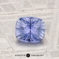 A 1.34-carat Ceylon sapphire with a cushion cut is shown on a textured gray surface, featuring the "Earth's Treasury" logo at the bottom.