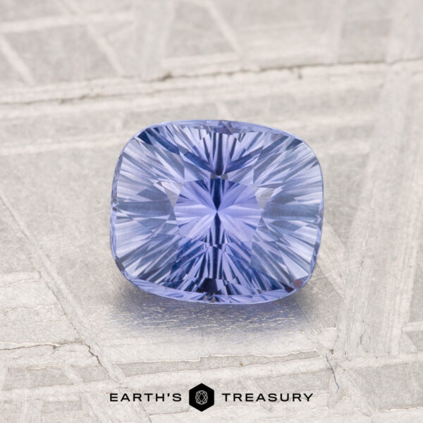1.34-Carat Ceylon Sapphire A 1.34-carat Ceylon sapphire with a cushion cut is shown on a textured gray surface, featuring the "Earth's Treasury" logo at the bottom.