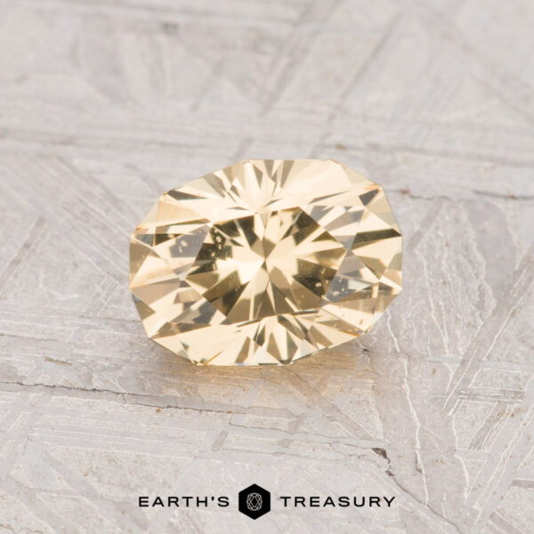 1.10-Carat Grossular Garnet A 1.10-carat yellow grossular garnet gemstone is displayed on a textured gray surface with the text "EARTH'S TREASURY" at the bottom.