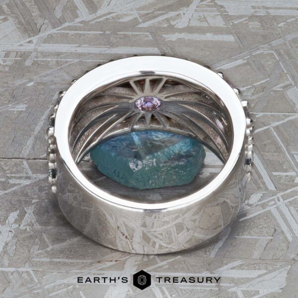 The Wide “Borealis” Ring in Blue-Violet Sapphire The Wide “Borealis” Ring in Blue-Violet Sapphire, featuring an intricate inner design, is shown upright on a rough blue stone with Earth's Treasury branding below.