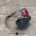 The "Saorise" ring in 14K white gold featuring a 1.86-carat pink Mahenge garnet is displayed on rough blue stone atop a textured gray surface, with "EARTH'S TREASURY" at the bottom to showcase its elegant design.