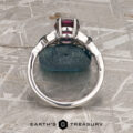 A 14K white gold "Saorise" solitaire ring with a 1.86-carat Mahenge garnet is displayed upright on a blue rock, with the Earth’s Treasury logo below.