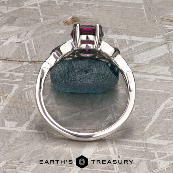 The "Saorise" ring in 14K white gold with 1.86-Carat Mahenge garnet A 14K white gold "Saorise" solitaire ring with a 1.86-carat Mahenge garnet is displayed upright on a blue rock, with the Earth’s Treasury logo below.