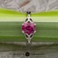 The "Saorise" ring in 14K white gold features a 1.86-carat rectangular Mahenge garnet atop an intricate band, displayed on a green leaf. The Earth's Treasury logo enhances its signature elegance inspired by Saoirse.