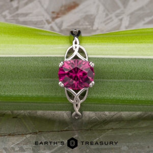 The "Saorise" ring in 14K white gold features a 1.86-carat rectangular Mahenge garnet atop an intricate band, displayed on a green leaf. The Earth's Treasury logo enhances its signature elegance inspired by Saoirse.