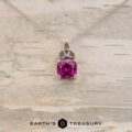 The "Saoirse" pendant in 14K white gold features a Celtic knot design and a 1.95-carat Mahenge garnet, shown against light wood with the Earth's Treasury logo. Ideal for anyone looking for unique, custom jewelry.