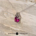 The "Saoirse" pendant in 14K white gold features a Celtic knot design and a 1.95-carat Mahenge garnet, shown on light wood with the "Earth's Treasury" logo—ideal for custom jewelry enthusiasts.