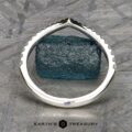 The Chevron Tapered Pave Diamond Band in platinum is displayed upright on a gray textured surface, with the "EARTH'S TREASURY" logo and text at the bottom.