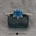 The Pave "Elenin" ring in platinum features a 1.21-carat round Montana sapphire and diamond accents, displayed on a dark textured rock with the Earth's Treasury logo below.