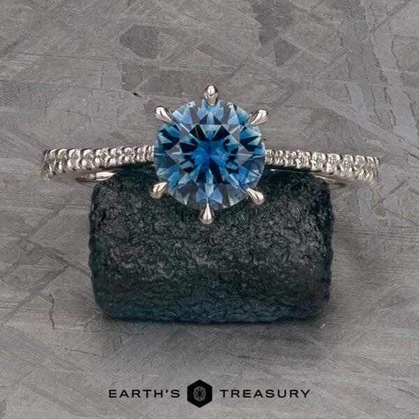 The Pave "Elenin" ring in platinum with 1.21-carat Montana sapphire The Pave "Elenin" ring in platinum features a 1.21-carat round Montana sapphire and diamond accents, displayed on a dark textured rock with the Earth's Treasury logo below.