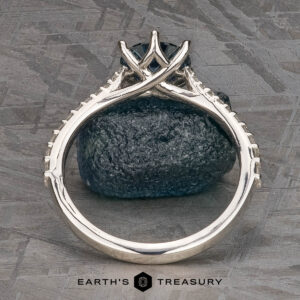 The Pave "Elenin" ring in platinum, featuring a 1.21-carat Montana sapphire, is displayed upright on a dark textured stone surface with the Earth's Treasury logo at the bottom.