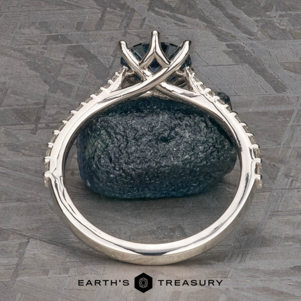 The Pave "Elenin" ring in platinum with 1.21-carat Montana sapphire The Pave "Elenin" ring in platinum, featuring a 1.21-carat Montana sapphire, is displayed upright on a dark textured stone surface with the Earth's Treasury logo at the bottom.