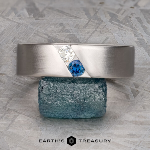 The "Parnis" ring in 14k white gold, brushed The "Parnis" ring in 14k brushed white gold features a white and a blue gemstone set diagonally, shown atop a rough blue-green crystal.