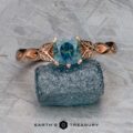 The "Kirryn" ring in 14k rose gold with a 1.07-carat Montana sapphire is displayed on a rough blue stone atop a textured gray background, with the Earth's Treasury logo visible below.