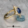 The "Francoise" ring in 18k yellow gold features a 2.28-carat oval Ceylon sapphire and surrounding diamonds, displayed on a rough blue crystal with the "Earth's Treasury" logo below.