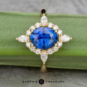 A 2.28-carat Ceylon sapphire is set in the "Francoise" ring with white diamonds in 18k yellow gold, displayed on a green background. The "Earth's Treasury" logo appears at the bottom.