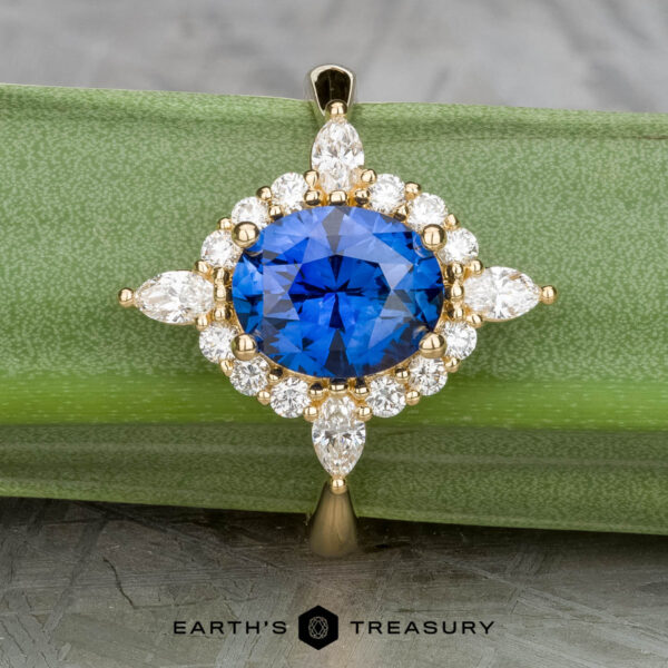 The "Francoise" ring in 18k yellow gold with 2.28-carat Ceylon sapphire A 2.28-carat Ceylon sapphire is set in the "Francoise" ring with white diamonds in 18k yellow gold, displayed on a green background. The "Earth's Treasury" logo appears at the bottom.