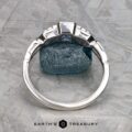 A platinum "Pallas" ring set with a 0.73-carat Montana sapphire stands upright against a rough blue stone on a textured gray surface, with the text "Earth's Treasury" below.