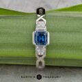 The "Pallas" platinum ring with a 0.73-carat Montana sapphire and sparkling side stones is displayed on a green leaf, with the Earth's Treasury logo at the bottom.