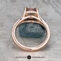 The "Senna" ring in 14k rose gold, featuring a 2.20-carat rectangular Umba sapphire and small diamonds, is displayed upright on a rough gray stone with the Earth's Treasury logo below.