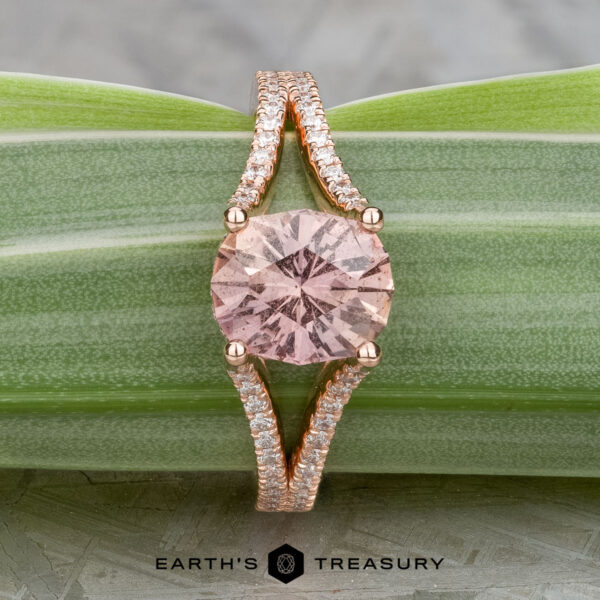 The "Senna" ring in 14k rose gold with 2.20-carat Umba sapphire The "Senna" ring features a 2.20-carat round pink Umba sapphire set in 14k rose gold with a split diamond band, shown on a green striped leaf.