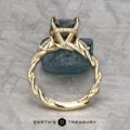 The "Lenore" ring in 14k yellow gold features a twisted, vine-like band and a 2.51-carat Australian sapphire, shown upright on textured stone. "EARTH'S TREASURY" appears at the bottom.