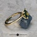 The Cathedral "Begonia" ring in 14k yellow gold, featuring a 2.27-carat Australian sapphire, stands upright on a rough blue stone with a textured gray background and the text "Earth's Treasury" below.