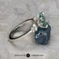 The Comet ring in platinum features a 3.53-carat Montana sapphire and small diamonds, displayed on a dark mineral rock; the Earth's Treasury logo is at the bottom.