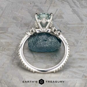 The Comet ring in platinum features a 3.53-carat Montana sapphire as its central stone, accented by smaller side stones, and is displayed upright on a textured stone background.