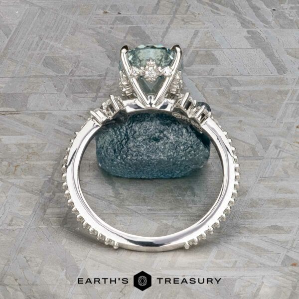 The Comet ring in platinum with 3.53-carat Montana sapphire The Comet ring in platinum features a 3.53-carat Montana sapphire as its central stone, accented by smaller side stones, and is displayed upright on a textured stone background.