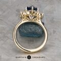 The "Angelica" ring in 14k white and yellow gold, featuring a 2.30-carat Montana sapphire, is shown upright on a rough blue stone with the Earth's Treasury logo below.