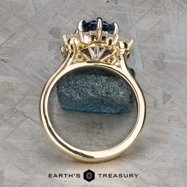 The "Angelica" ring in 14k white and yellow gold with 2.30-carat Montana sapphire The "Angelica" ring in 14k white and yellow gold, featuring a 2.30-carat Montana sapphire, is shown upright on a rough blue stone with the Earth's Treasury logo below.