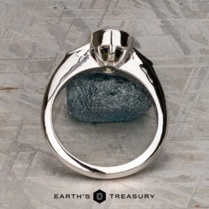 The "Ceres" ring in 14K white gold with a 2.52-carat Madagascar sapphire is displayed upright on a textured stone surface, featuring the Earth's Treasury logo at the bottom.