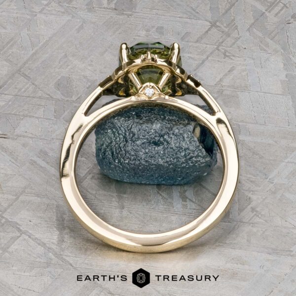 The "Marisol" ring in 14k yellow gold with 2.90-carat Australian sapphire The "Marisol" ring in 14k yellow gold with a 2.90-carat Australian sapphire stands upright on a rough stone surface, featuring the Earth's Treasury logo at the bottom.
