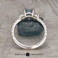 The Pave "Dryope" ring in platinum features a 1.15-carat Montana sapphire centerpiece and side stones, displayed upright on a rough blue mineral with the Earth's Treasury logo below.